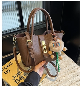 Detail of dark brown lychee pattern bucket bag with lion plush pendant and gold lock