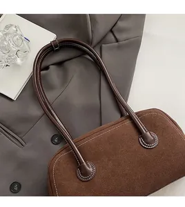 Detail of dark brown suede Boston bag with white stitching and smooth leather handle