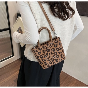 Détail du sac seau à motif léopard avec poignées brunes et bandoulière réglable