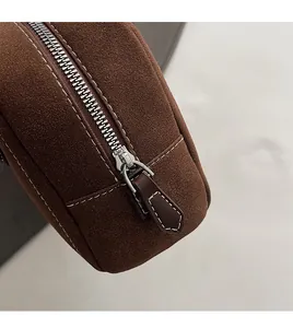Detail of smooth silver zipper and stitching on brown suede Boston shoulder bag