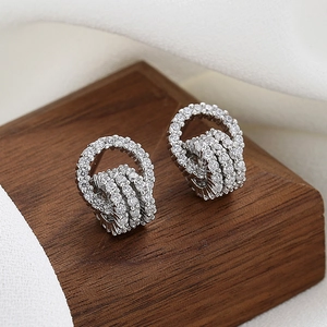 Elegant multi-layer silver hoop earrings with shimmering cubic zirconia on wooden stand