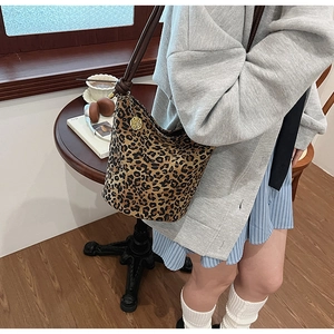 Detailed shot of leopard print bucket bag with gold rose pendant in a lifestyle setting