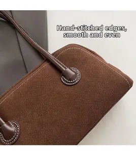 Macro detail of hand-stitched white seams on dark brown faux suede boston bag texture