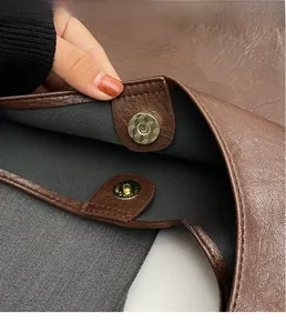 Detail of lychee textured brown leather tote bag with gold magnetic snap closure