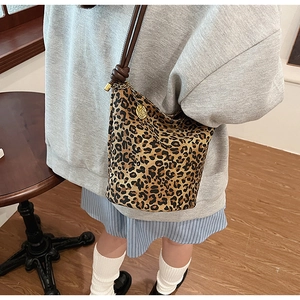 Detail of leopard print bucket bag with braided strap and golden rose charm accessory