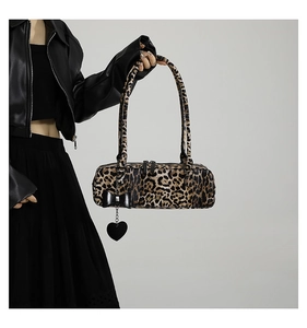 Detail of leopard print bolster bag with black ribbon bow and silver heart pendant