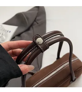 Detail view of silver metal rivets and stitching on brown suede Boston handbag handles