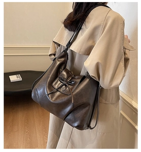 Close-up of a vintage dark brown tote bag with bow detail worn by a model in a beige coat