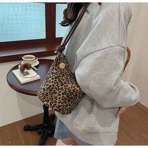 Detail view of leopard print bucket bag with brown rope strap and gold flower charm