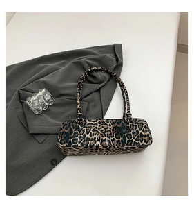Detail of rectangular leopard print shoulder bag displayed on a sleek blazer background