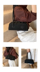 Detail of minimalist black tote bag featuring contrasting white stitching and double zippers