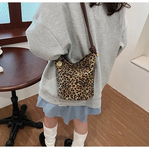 Close-up of leopard print bucket bag with long brown strap and gold flower charm