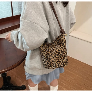 Close-up of leopard print bucket bag with leather strap on a stylish model