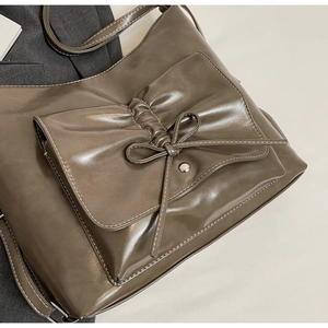 Detail of vintage brown shoulder bag showing bow pocket design and white contrast stitching