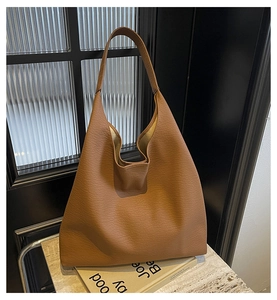 Detail of a large brown hobo tote bag in lychee pattern leather on a stone surface