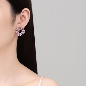 Elegant silver flower earrings with red teardrop stones and diamonds on model