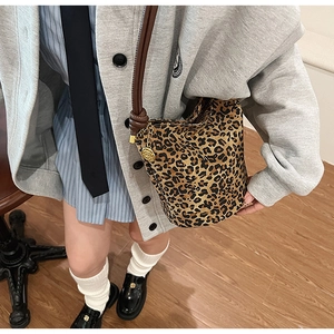 Detailed view of leopard print bucket bag with gold rose pendant and brown strap