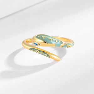 Punk style gold snake open ring with green enamel and blue zircon on white podium