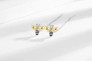Detailed view of bee-shaped drop earrings with silver chains and gold accents
