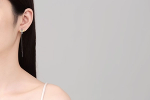 Close-up of model wearing long bee dangle earrings with two-tone finish and delicate chains