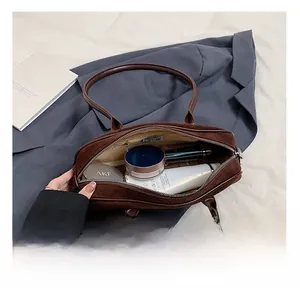Spacious interior of dark brown suede shoulder bag showing storage for cosmetics