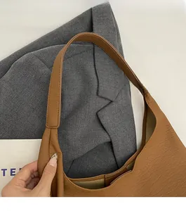 Detail of caramel tote bag showing soft pebble leather texture and wide shoulder strap