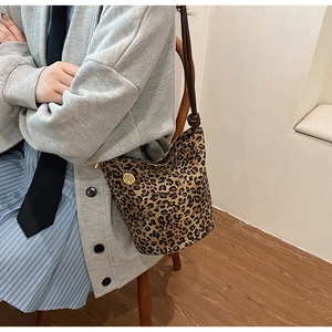 Detail of leopard print bucket bag with golden metal charm and brown shoulder strap