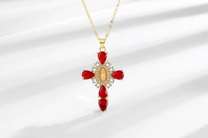 Macro view of gold cross necklace with red pear stones and virgin mary relief