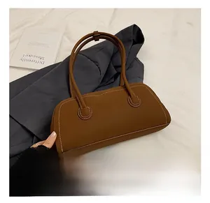 Brown tote bag detail featuring contrast white stitching and long shoulder straps