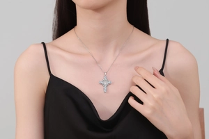 Close-up of a zircon micro-paved cross necklace on a model wearing black silk