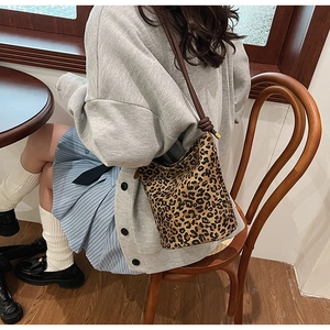 Detailed view of leopard print bucket bag with brown rope strap worn on shoulder