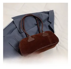Detailed view of a brown suede rectangular handbag on a blue blazer and white fabric