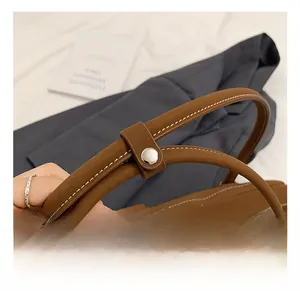 Detail of brown leather tote with white contrast stitching and silver metal zipper closure