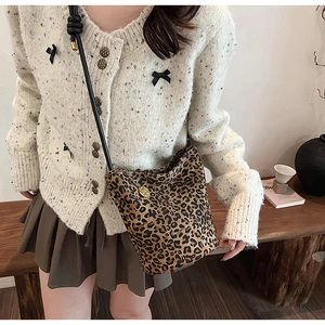 Close-up detail of leopard print canvas bucket bag texture with slim black shoulder strap