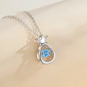Elegant silver crown necklace with dancing blue water-drop pendant on beige background