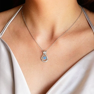 Elegant silver crown teardrop necklace with a blue gemstone on a female neck