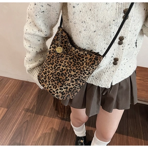Detail of leopard print bucket bag with golden rose charm and black shoulder strap