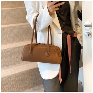 Detail of brown leather tote with contrast white stitching and slender shoulder handles
