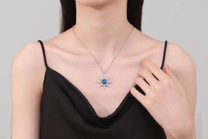 Close-up of a silver star pendant necklace with a blue center stone worn on a model's neck