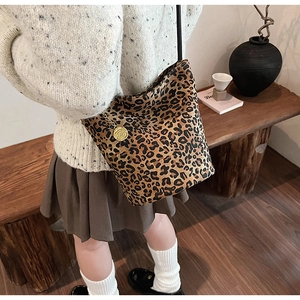 Detail of leopard print bucket bag with golden rose charm on a small shoulder strap