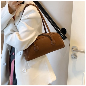 Close-up of a dark brown leather tote bag featuring elegant white contrast stitching