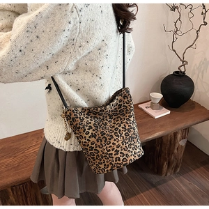 Detail of leopard print bucket bag with gold coin charm and black shoulder strap