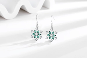 Detailed view of silver snowflake earrings with green marquise stones and zircons