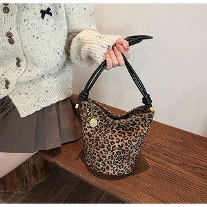 Detail of leopard print bucket bag featuring rope handles and gold camellia charm