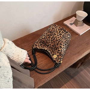 Detail of leopard print bucket bag with braided knot handle and gold flower charm