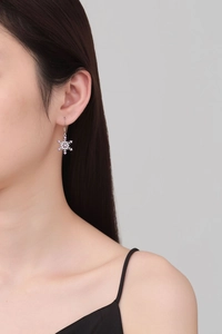 Detail of snowflake drop earring with silver finish and pink crystal stones on model