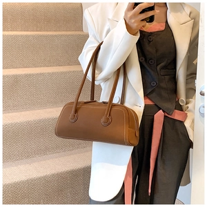 Detailed view of brown leather bowling bag with contrast stitching on outdoor stairs