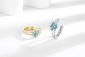 Detail of flower ring with blue petals, pearls, and crystals on a white background