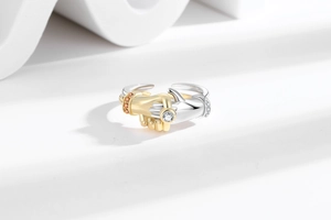 Detail of silver hugging hands ring with round zircon and gold sleeves set with orange stones