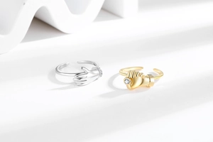 Detail of adjustable hug and fist rings featuring sparkling zircon stones and metallic finish